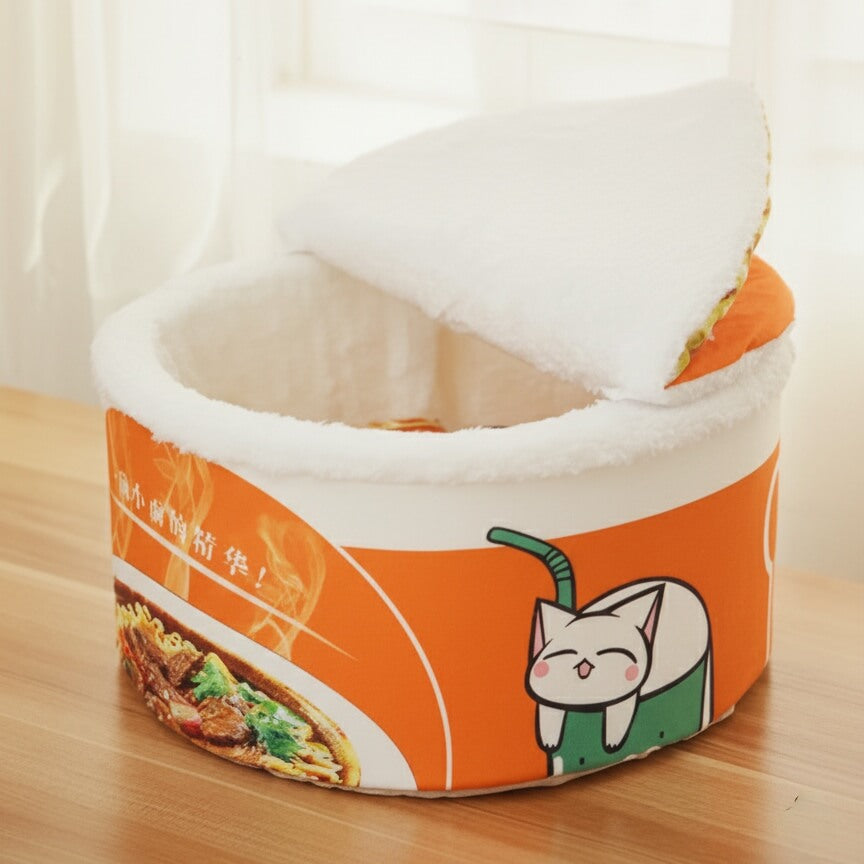 Panier cachette CoconPattes, lit tasse de nouilles ramen ouvert, mettant en évidence l'intérieur chaud et les motifs ludiques sur l'extérieur orange.