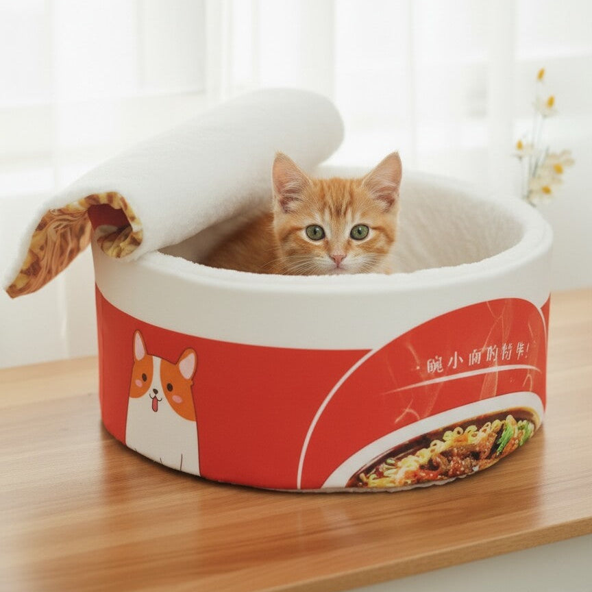 Chaton roux se blottissant dans le lit panier tasse de nouille CoconPattes orange et blanc, une cachette chaude et douillette pour les chats. 