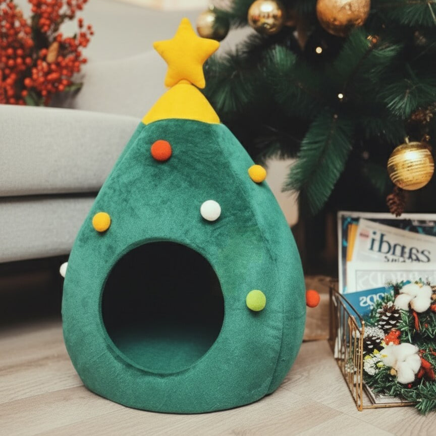 Lit douillet CoconPattes pour chat en forme de sapin de Noël vert, décoré de pompons et étoile jaune, parfait pour une cachette festive sous le sapin.